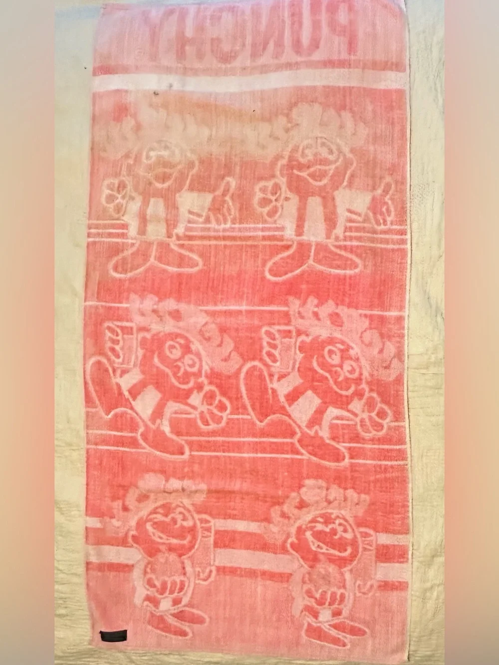 Pink and white 70s beach towel featuring Punchy, the Hawaiian Punch Mascot
